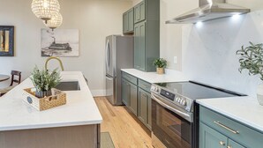 Uma cozinha moderna com uma ilha central, eletrodomésticos de aço inoxidável e um lustre.