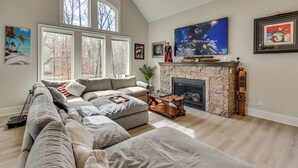 Ein Wohnzimmer mit Ecksofa, Kamin und Kunstwerken an den Wänden.