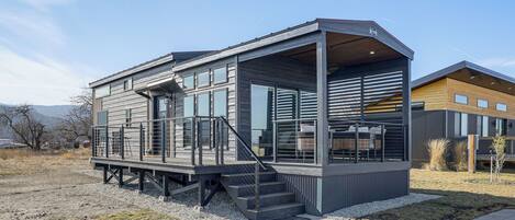 A modern house with a covered porch, a staircase, and a deck.
