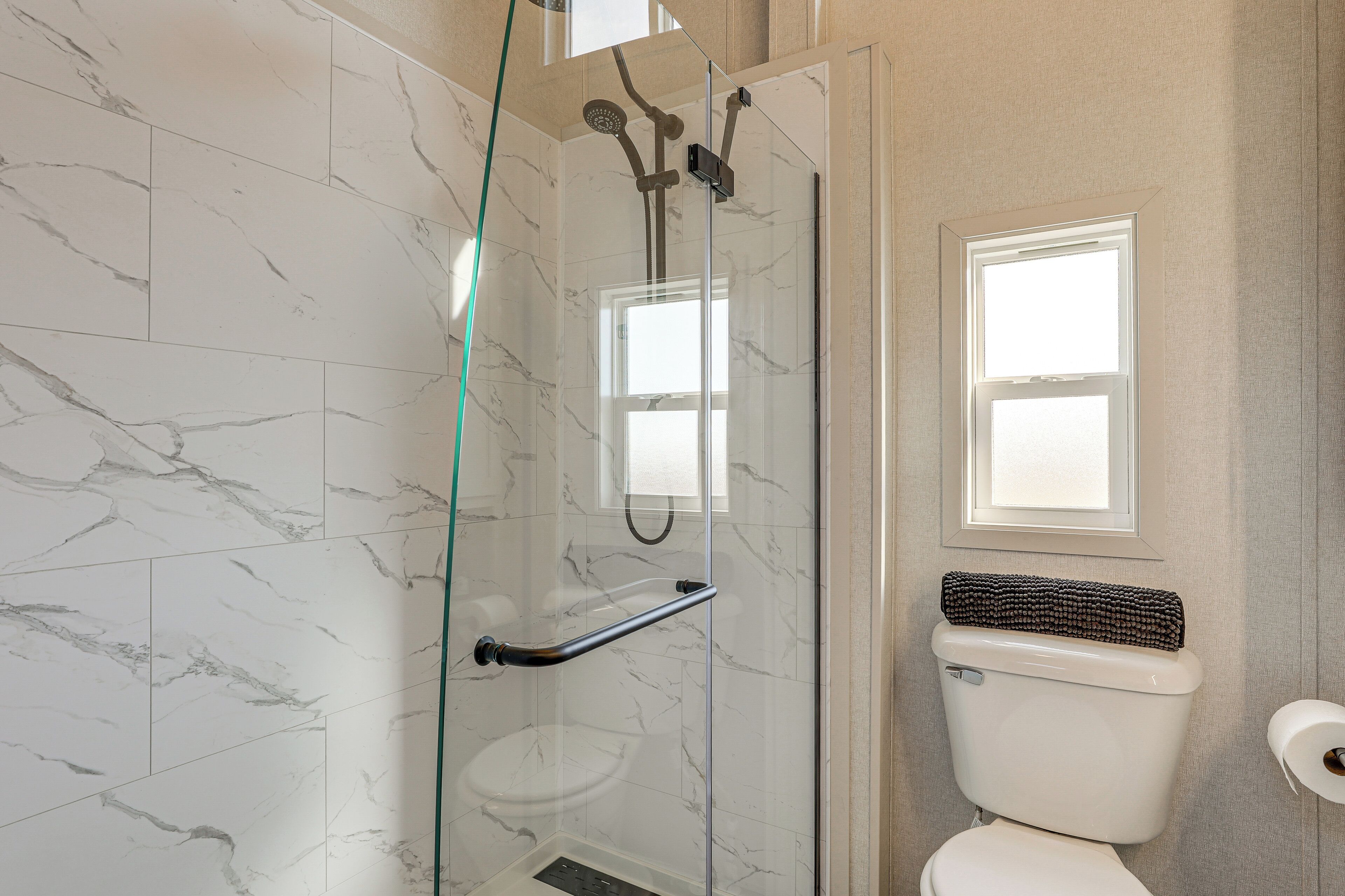 Un baño con ducha de vidrio, inodoro y ventana.