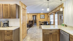 A kitchen with wooden cabinets, a coffee maker, and a dining area with chairs and a table. - Waterfront Leech Lake Cabin w/ Boat Dock + Lift (Walker)