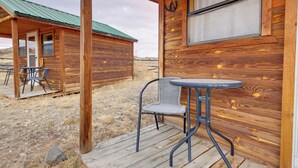 A wooden cabin with a porch, a table, and two chairs. - Mtn-view Ranch Retreat in Western Wyoming! (Thermopolis)