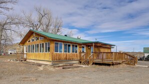 A wooden building with a green roof, large windows, and a wooden deck. - Mtn-view Ranch Retreat in Western Wyoming! (Thermopolis)
