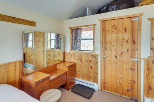 Un dormitorio con muebles de madera, una ventana con cortinas estampadas y una puerta.