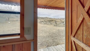 A wooden door leading to an outdoor area with a wooden deck and a view of a fenced field.