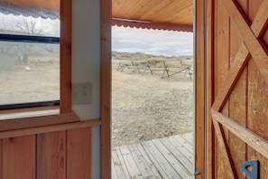 A wooden door leading to an outdoor area with a wooden deck and a view of a fenced field. - Scenic & Unique Country Retreat in Thermopolis! (Thermopolis)