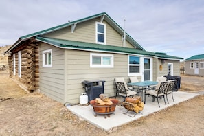 A cabin with a stone exterior, a green roof, and a patio with a table and chairs. - Cattle Ranch Home in Western Wyoming w/ Grill (Thermopolis)