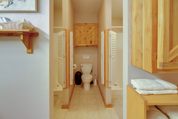 A narrow bathroom with a toilet, wooden cabinets, and a shelf with towels. - Cattle Ranch Home in Western Wyoming w/ Grill (Thermopolis)