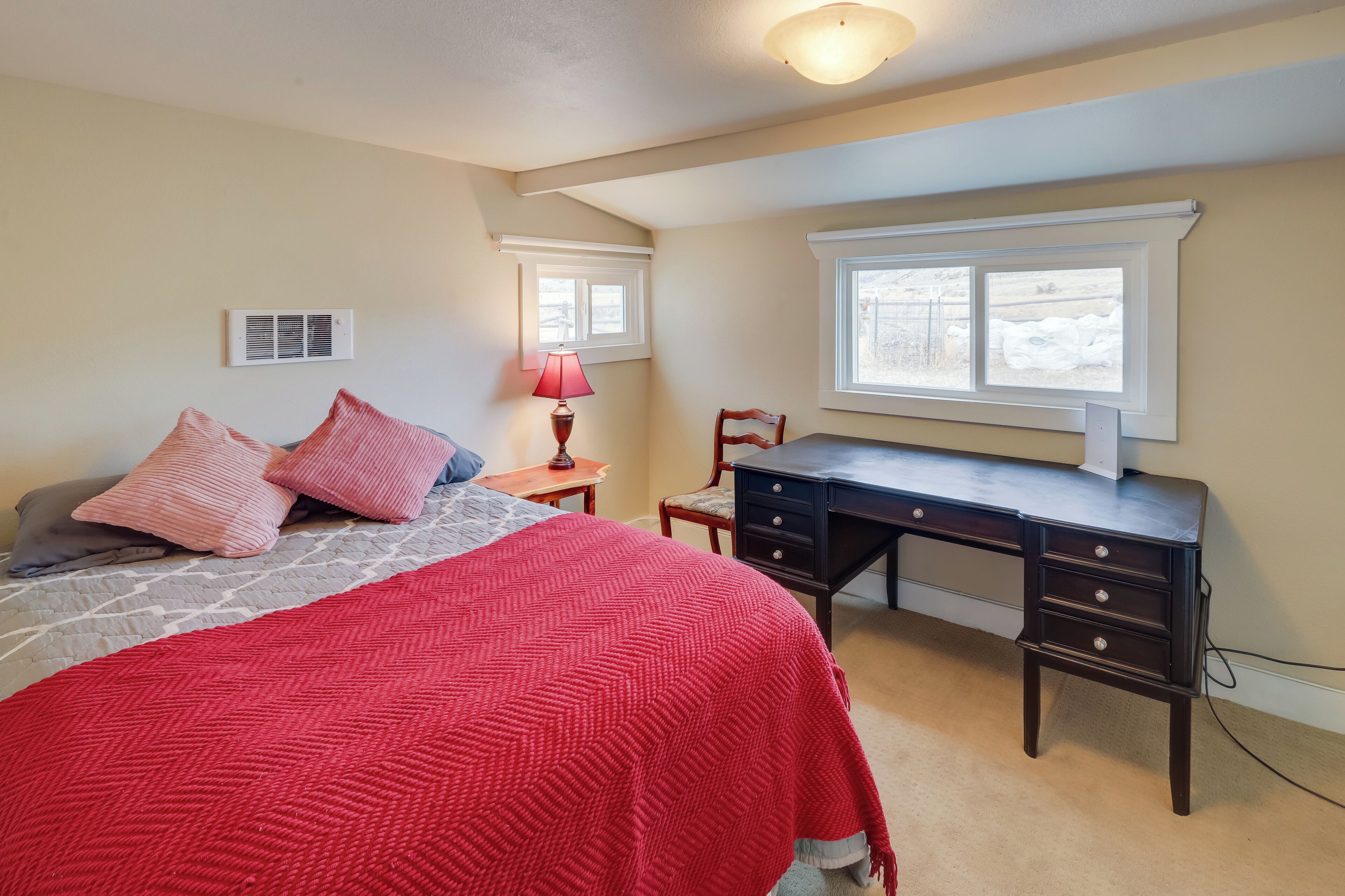A bedroom with a bed, a desk, a chair, and a window.