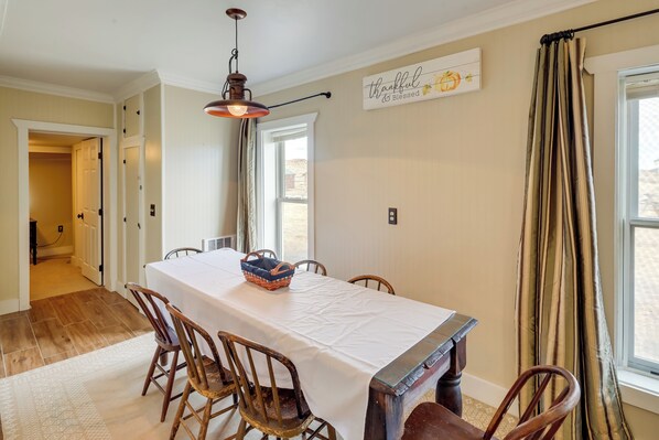 A dining room with a long table, wooden chairs, a basket, and a wall sign. - Cattle Ranch Home in Western Wyoming w/ Grill (Thermopolis)