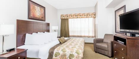 A hotel room with a bed, a TV, a chair, a desk, and a window with curtains.