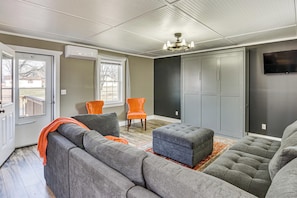 A living room with a sectional sofa, an ottoman, a chair, a chandelier, and a TV mounted on the wall. - Shenandoah Valley Retreat: Hike, Fish & Explore! (Broadway)