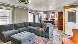 A living room with a sectional sofa, ottoman, and a small orange chair.