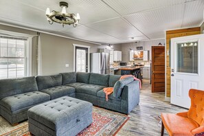 A living room with a sectional sofa, ottoman, and a small orange chair. - Shenandoah Valley Retreat: Hike, Fish & Explore! (Broadway)