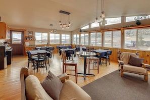 A spacious dining area with wooden tables and chairs, large windows, and a view of the outdoors. - On Ranch w/ Stunning Mtn Views! Thermopolis Escape (Thermopolis)