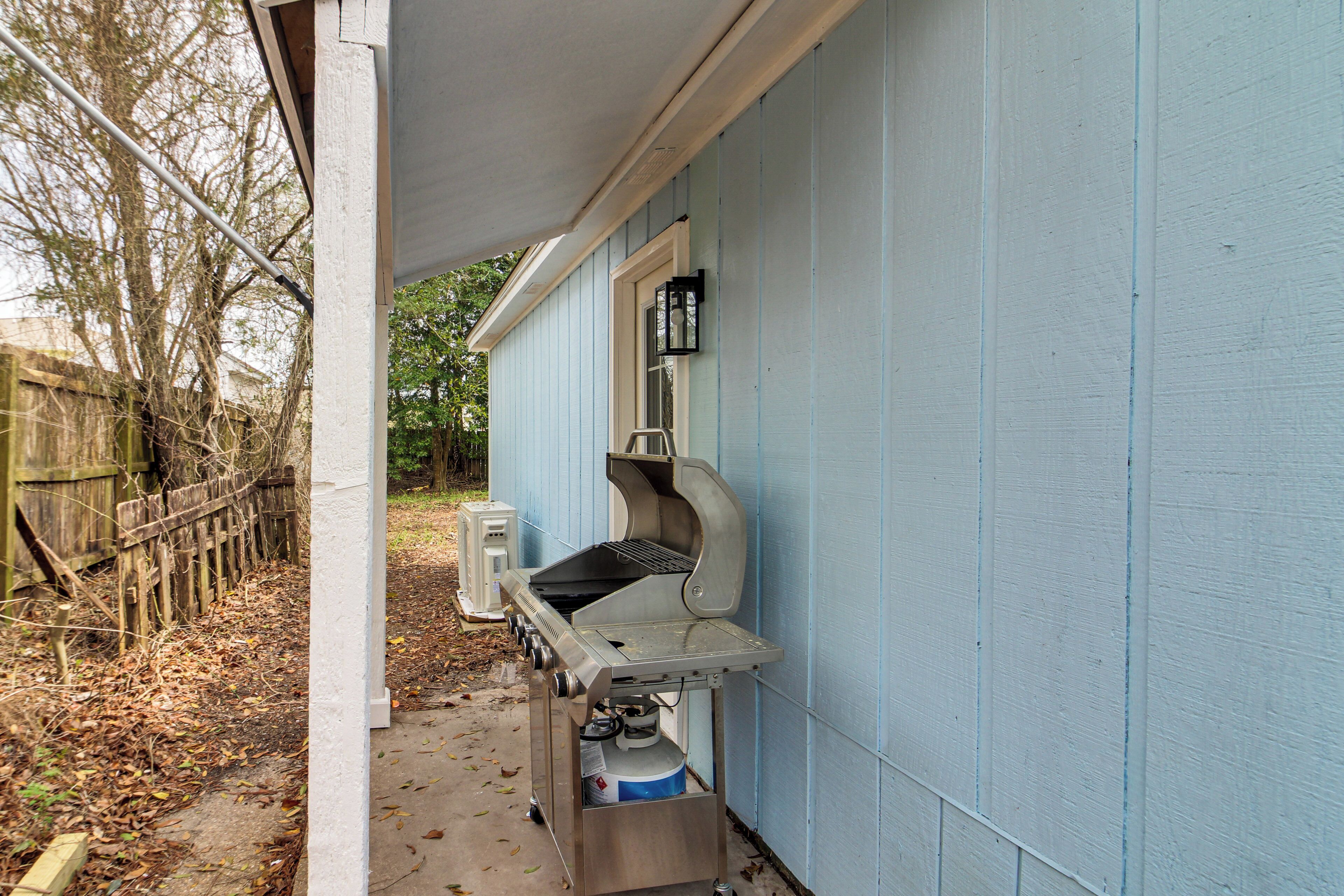 A portable grill setup against a light blue house exterior.