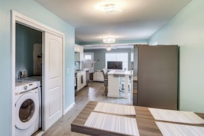 A modern kitchen with a built-in washer, a dining area with a table, and a large refrigerator. - Fun in the Sun w/ Family - Pensacola Duplex + Yard (Pensacola)