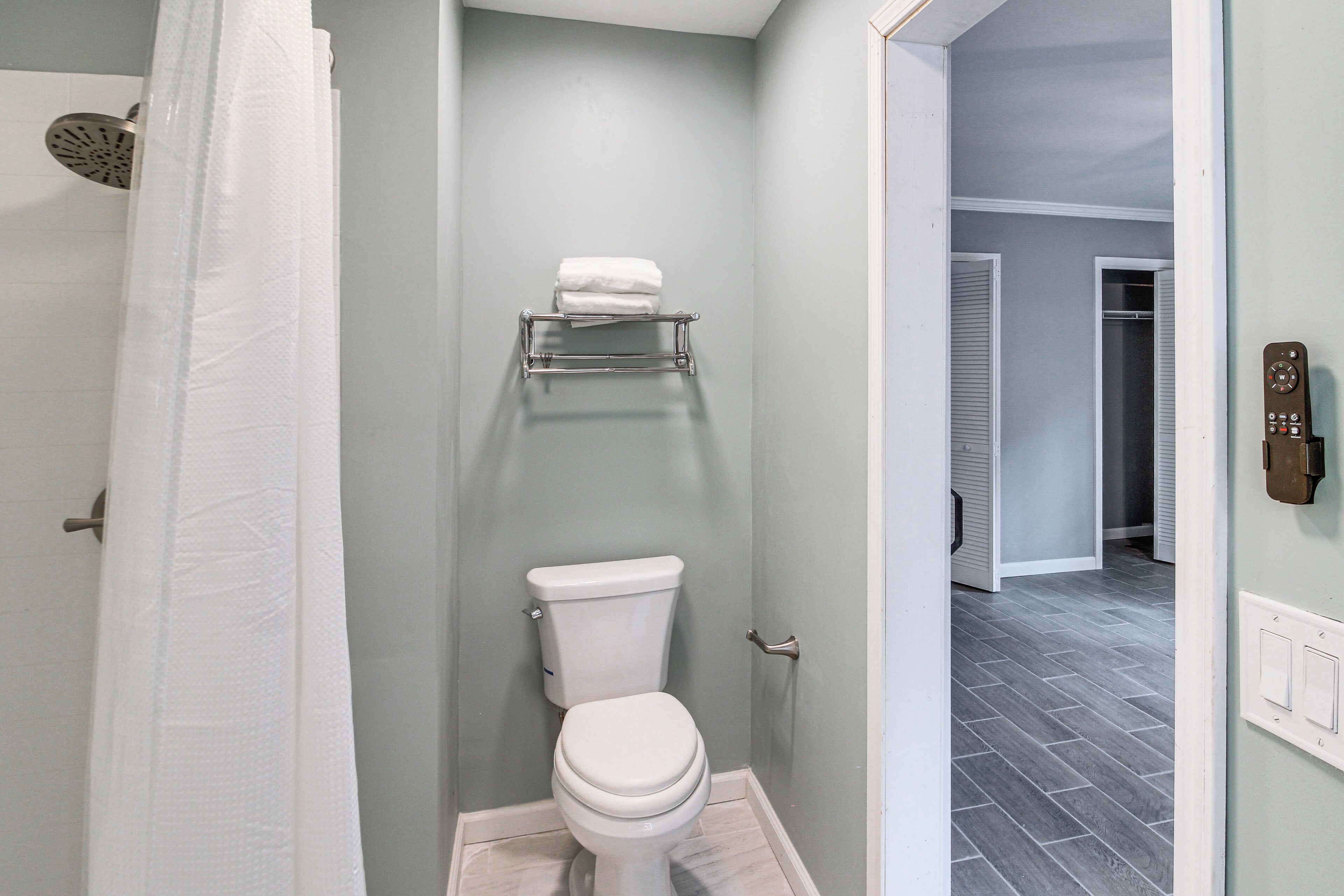 A bathroom with a toilet, a towel rack, and a shower curtain.