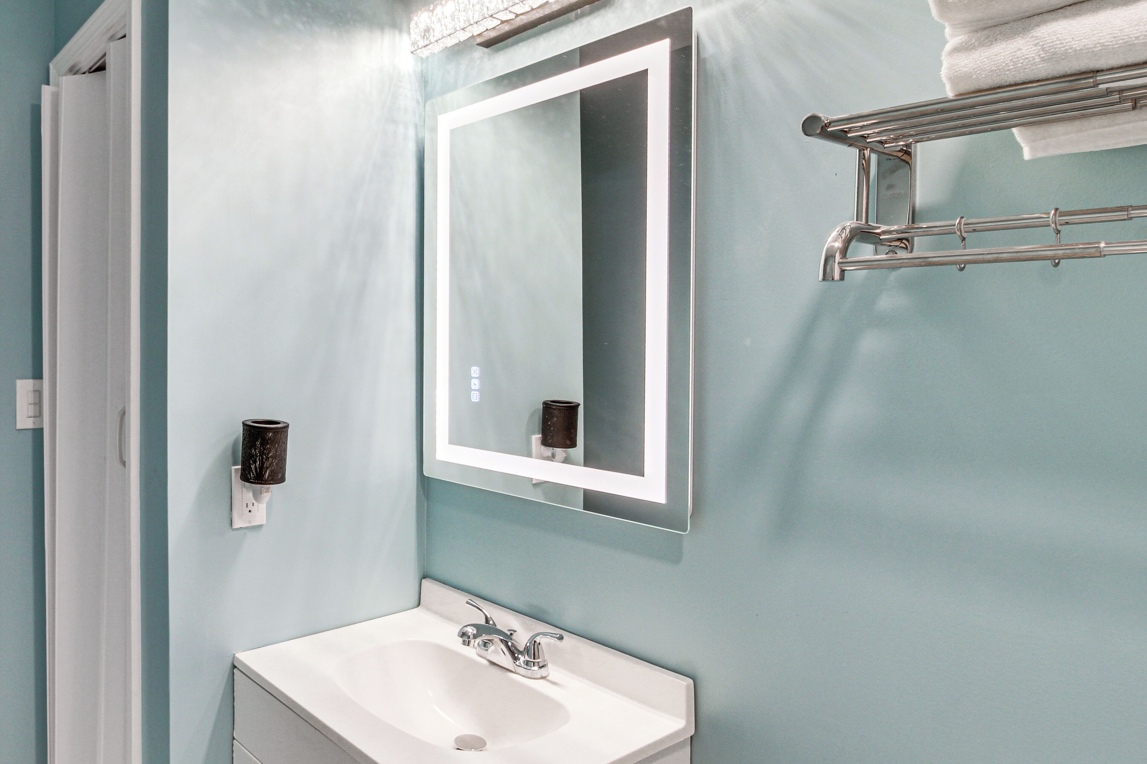 Une salle de bain avec un lavabo blanc, un miroir et un porte-serviettes.