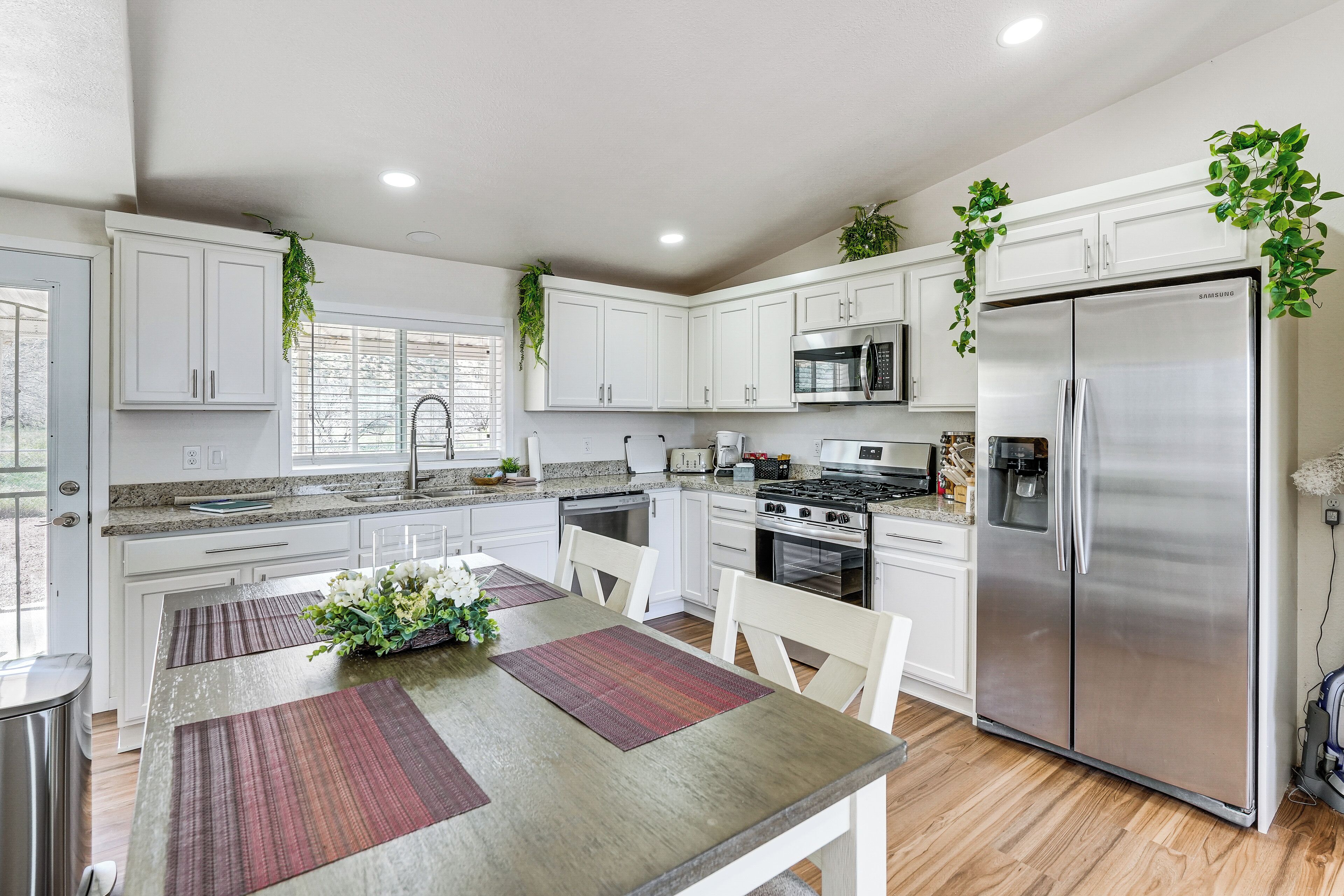 A modern kitchen with white cabinets, stainless steel appliances, and a dining area with a table and chairs.