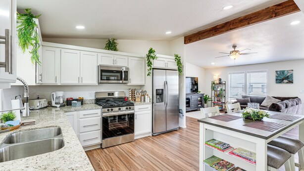 A modern kitchen with white cabinets, stainless steel appliances, and wooden flooring.