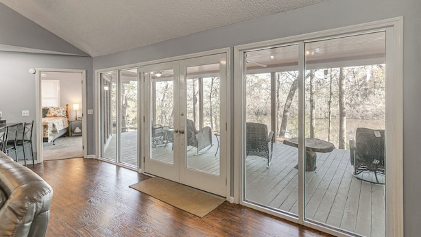 A spacious room with a large sliding glass door leading to an outdoor deck with outdoor furniture. - Private Dock + River View: Cabin Retreat in Jesup (Jesup)