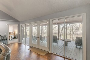 A spacious room with a large sliding glass door leading to an outdoor deck with outdoor furniture. - Private Dock + River View: Cabin Retreat in Jesup (Jesup)