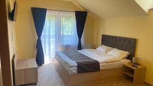 Un dormitorio con cama, mesita de noche, cortinas y un radiador.