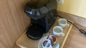 Una cafetera, dos tazas blancas y una bandeja con leche condensada para café.