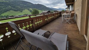 A wooden deck with a view of green hills and mountains. - 5_3 Chalet Noriker by Interhome (Niedernsill)
