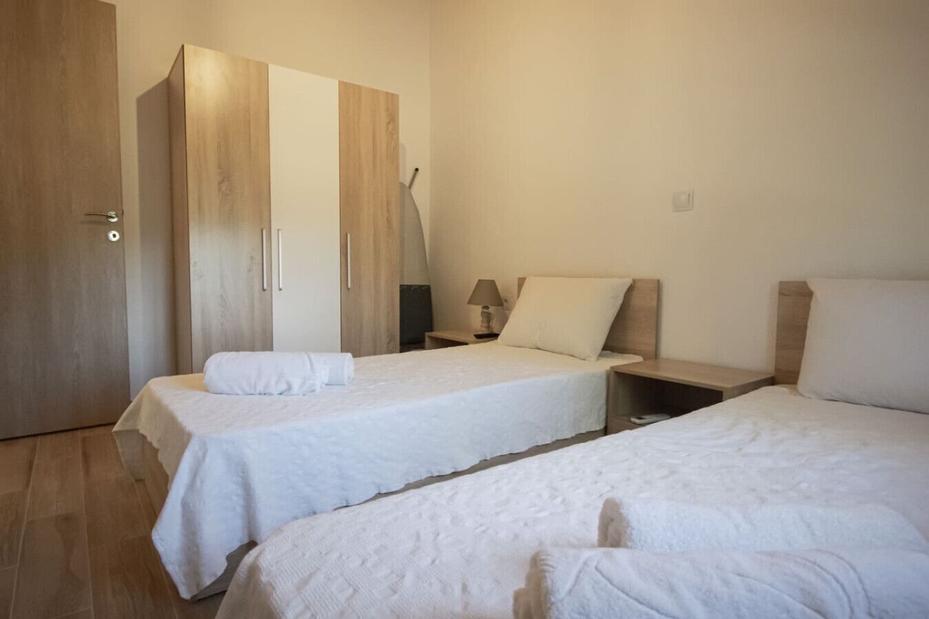 Una habitación con dos camas, un armario, una lámpara y una mesita de noche.