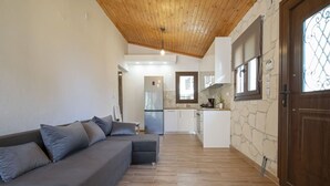 Un soggiorno moderno con divano, pavimento in legno e una cucina sullo sfondo.