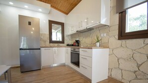 Una cucina moderna con mobili bianchi, un frigorifero in acciaio inossidabile, un forno e una parete in pietra.