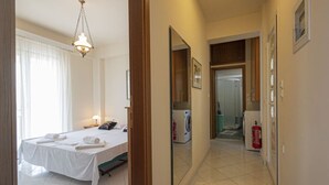 Ein Hotelzimmer mit einem Bett, einer Waschmaschine, einem Feuerlöscher und einem Flur zu weiteren Zimmern.