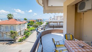 Ein Balkon mit Tisch und Stühlen, mit Blick auf ein Wohngebiet mit Häusern und blauem Himmel.