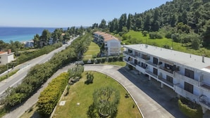 Eine Luftaufnahme einer Küstenlandschaft mit einem Gebäudekomplex, einer gewundenen Straße und freiem Blick auf das Meer.