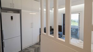 Eine moderne Küche mit weißen Schränken, einem integrierten Kühlschrank und einem großen Fenster mit Blick auf einen Balkon.
