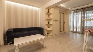 Ein Wohnzimmer mit einem schwarzen Sofa, einem weißen Couchtisch und einer eingebauten Regalanlage mit Dekorationselementen.
