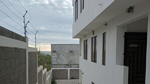 A narrow alleyway with a white building on the right, a brick wall on the left, and a view of the sea in the distance. - Charming 2-bedroom apartment with AC in sunny Playas (Playas)
