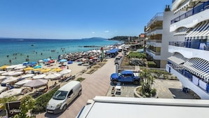 Un hotel sulla costa con vista sulla spiaggia, diversi balconi e un'area parcheggio.