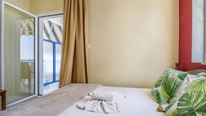 Una stanza con un letto, una finestra con tende, una porta scorrevole e una parete rossa.