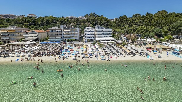 Una spiaggia con acqua cristallina, ombrelloni e persone.