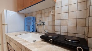 Una cocina con un lavabo blanco, una estufa negra y un dispensador de agua azul.