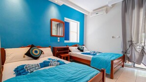 Una habitación con dos camas, una ventana con persianas, un espejo, una mesita y un equipo de aire acondicionado.
