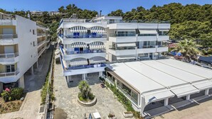 Un hotel a più piani con balconi, un’area parcheggio coperta e un cortile con piante.