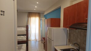 Habitación de hotel compacta con kitchenette, cama, baño y vista a la calle.