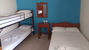 Una habitación con literas, una cama individual, una pequeña mesa de madera y un espejo en la pared.