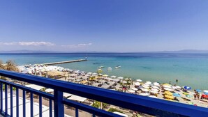 Ein Strand mit Sonnenschirmen, Liegestühlen und einem Steg, der ins Meer führt.