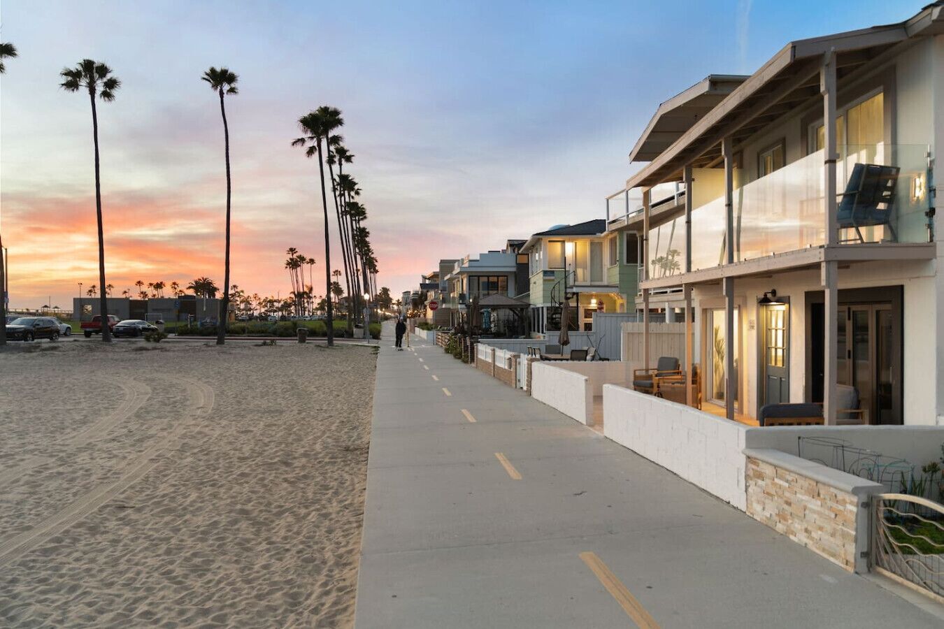 A beachfront property with a sidewalk, palm trees, and a row of houses.