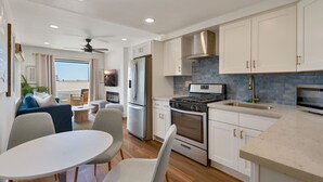 Una cucina moderna con mobili bianchi, forno integrato, piano cottura e lavello. C'è un'area pranzo con tavolo e sedie.